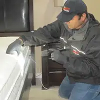 Bed bug inspection technician checking a mattress and bed frame for signs of infestation in Honolulu, HI