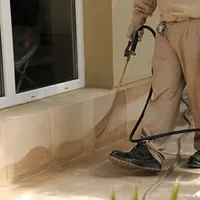 General pest control technician spraying exterior perimeter around a home in Honolulu, HI