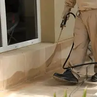 General pest control technician spraying exterior perimeter around a home in Honolulu, HI