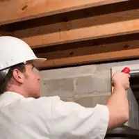 Termite inspection technician checking a basement wall and framing for termite activity in Honolulu, HI